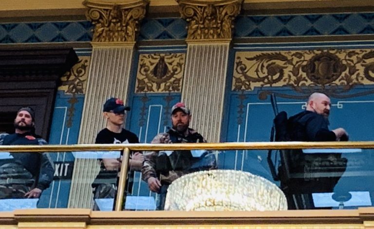 Hundreds of protesters, some carrying guns in the state Capitol, demonstrate against Michigan’s emergency measures